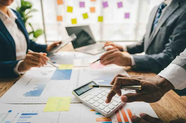 Accounting for Startups – startup business team reviewing financial reports, bookkeeping records, cash flow, budgeting, and tax planning with financial charts and a calculator.